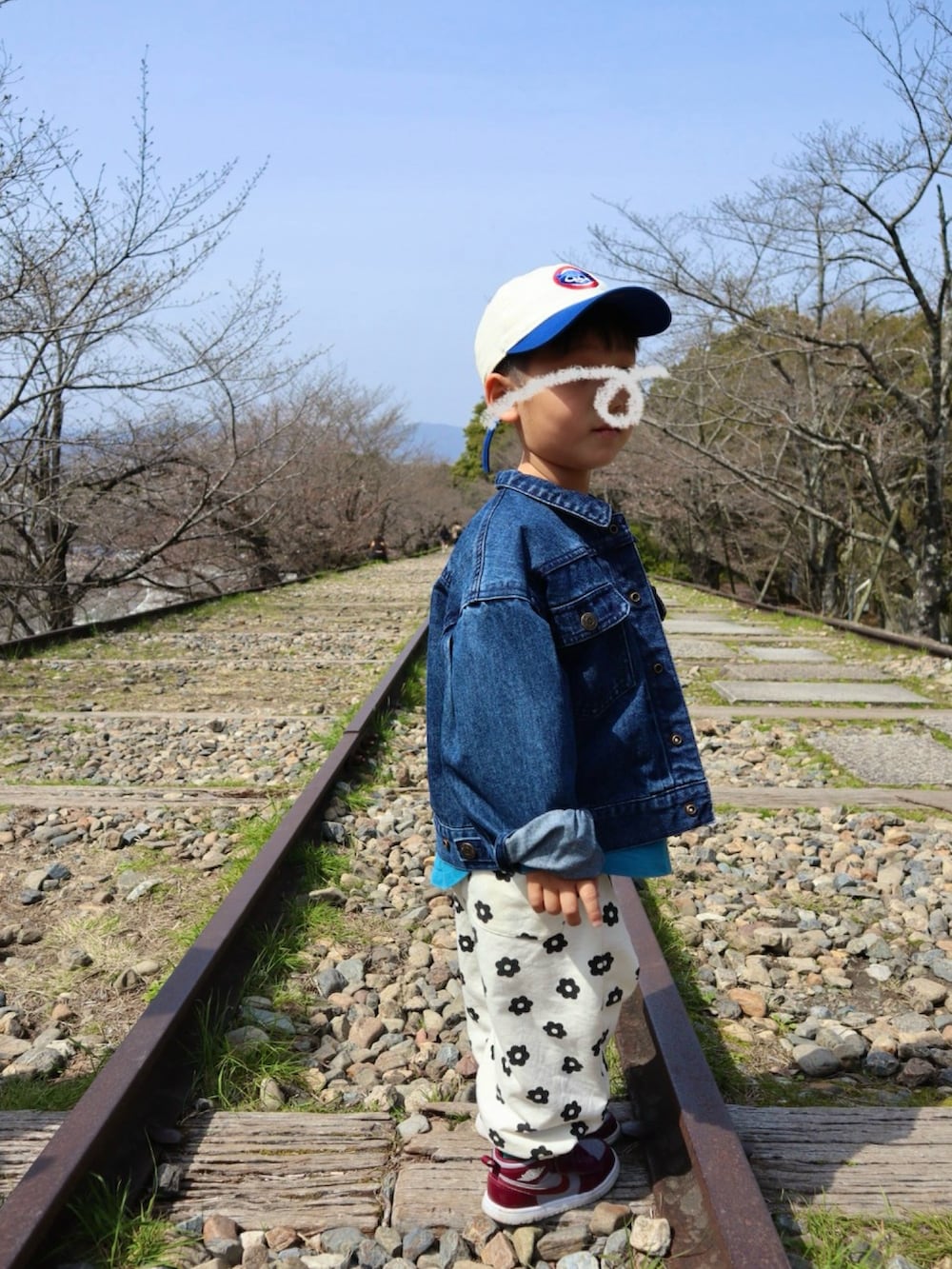 ブルー系のデニムジャケット、ブルー系のTシャツ/カットソー、ホワイト系のスウェットパンツを着用したキッズの春コーディネートの2枚目の写真