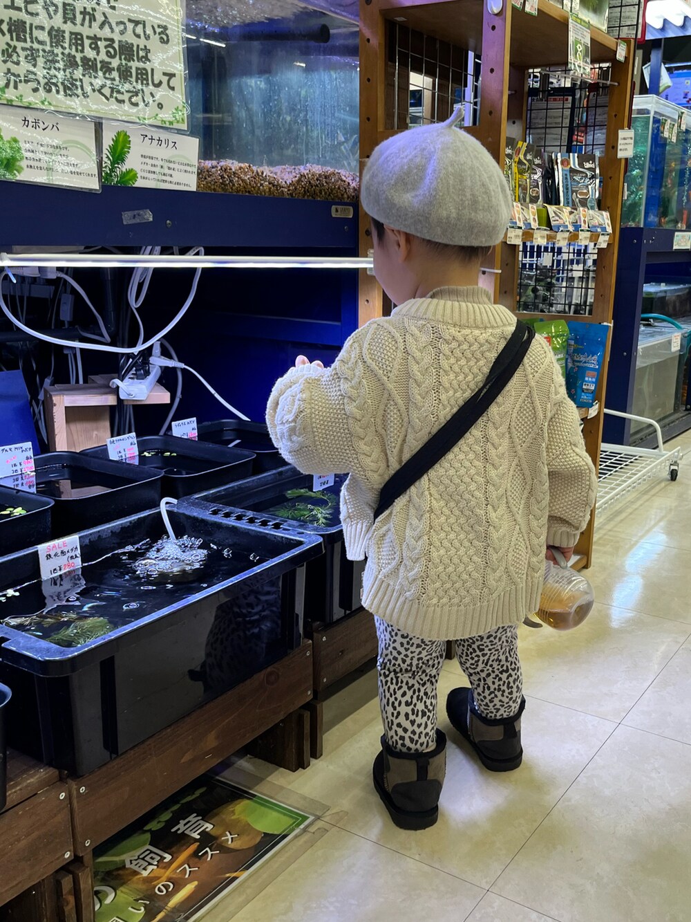 ホワイト系のニット/セーター、ブラック系のショルダーバッグ、ブラック系のブーツを着用したキッズの冬コーディネートの2枚目の写真