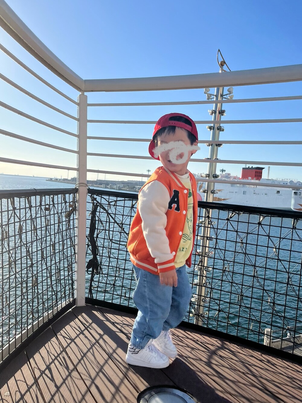 イエロー系のスウェット、オレンジ系のスタジャン、ブルー系のデニムパンツを着用したキッズの冬コーディネートの2枚目の写真