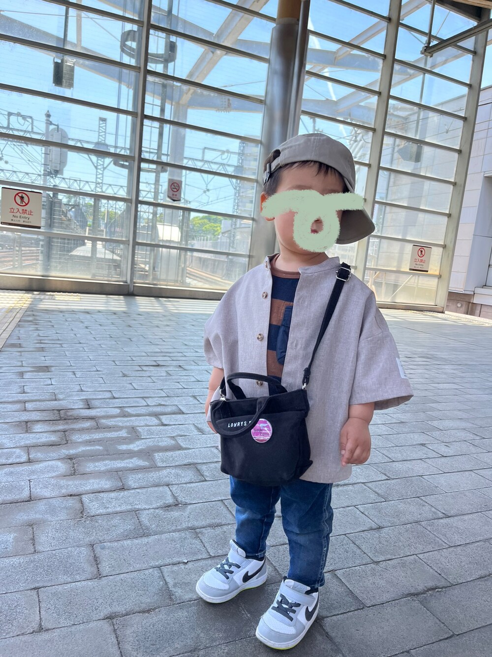 グリーン系のワンピース、ブルー系のデニムパンツ、ブラウン系のサンダルを着用したレディースの春コーディネートの2枚目の写真