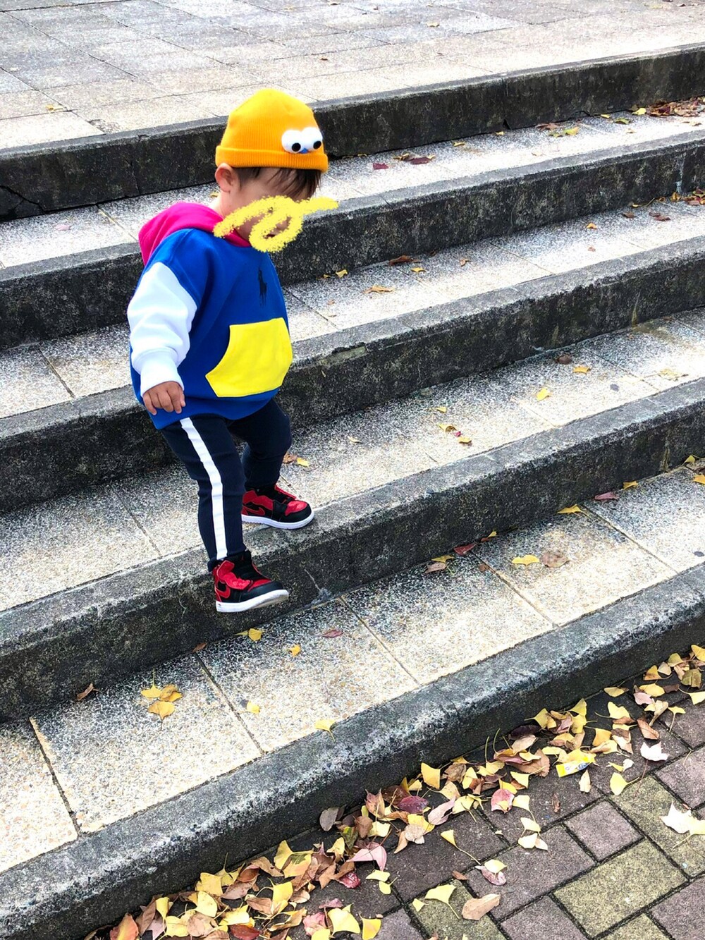 イエロー系のパーカー、ブラック系のワンピース、ブラウン系のスニーカーを着用したレディースの秋コーディネートの2枚目の写真