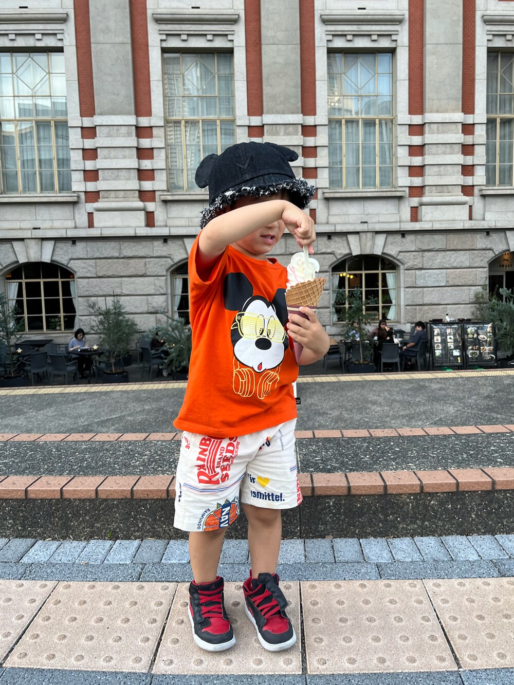 オレンジ系のTシャツ/カットソー、ホワイト系のパンツ、レッド系のスニーカーを着用したキッズの春コーディネートの3枚目の写真