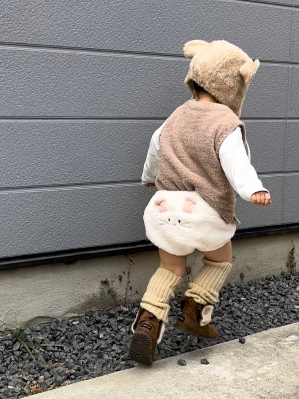 ベージュ系のベスト、ホワイト系のパンツ、ブラウン系のブーツを着用したキッズの冬コーディネートの3枚目の写真