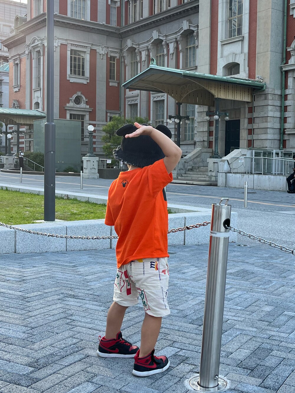 オレンジ系のTシャツ/カットソー、ホワイト系のパンツ、レッド系のスニーカーを着用したキッズの春コーディネートの2枚目の写真