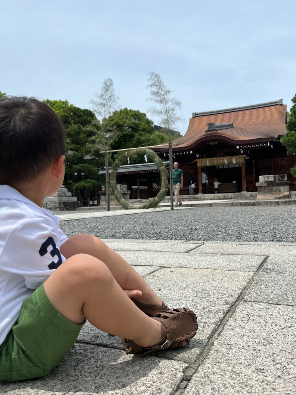 ホワイト系のポロシャツ、グリーン系のパンツ、ブラウン系のサンダルを着用したキッズの夏コーディネートの3枚目の写真