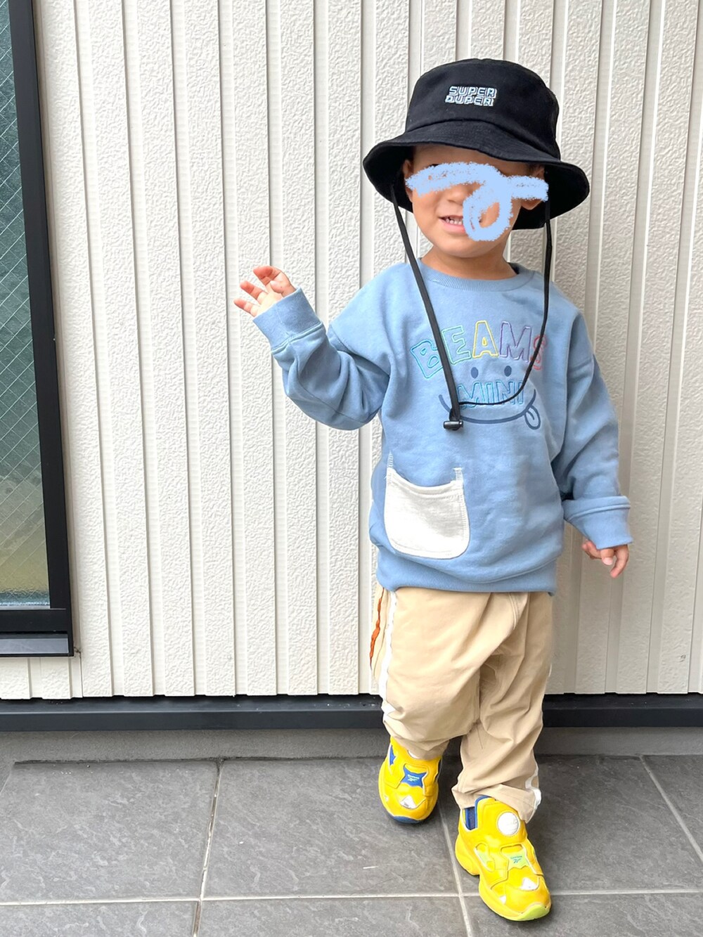 ブルー系のスウェット、ベージュ系のパンツ、イエロー系のスニーカーを着用したキッズの秋コーディネートの2枚目の写真