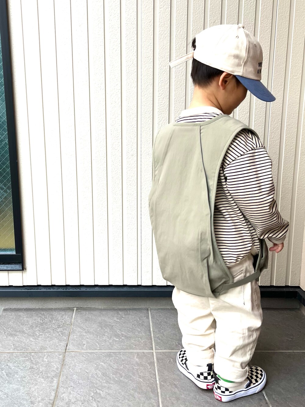 グリーン系のベスト、ホワイト系のTシャツ/カットソー、ホワイト系のデニムパンツを着用したキッズの春コーディネートの2枚目の写真
