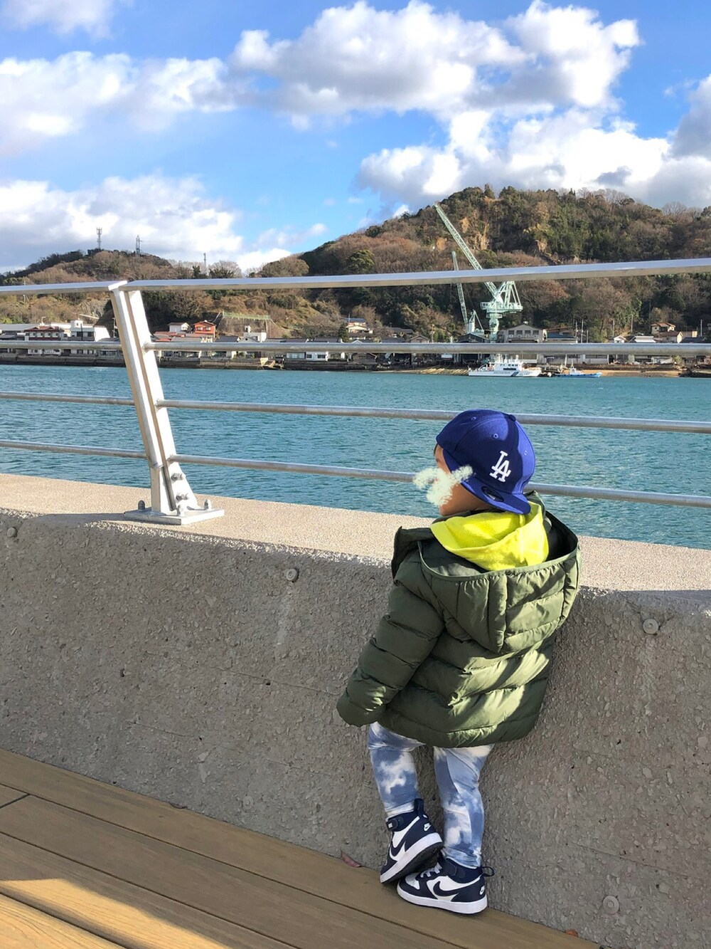 グリーン系のパーカー、ブラック系のパンツ、ホワイト系のスニーカーを着用したレディースの冬コーディネートの2枚目の写真