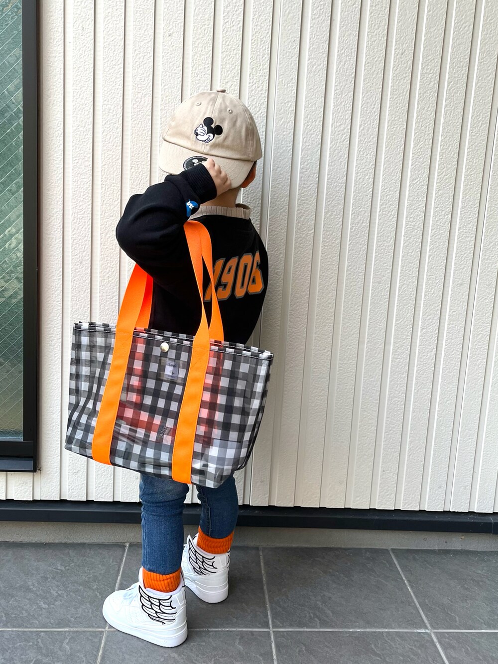 ブラック系のスウェット、ブルー系のデニムパンツ、ブラック系のトートバッグを着用したキッズの冬コーディネートの3枚目の写真