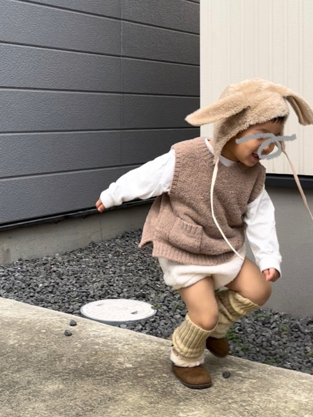 ベージュ系のベスト、ホワイト系のパンツ、ブラウン系のブーツを着用したキッズの冬コーディネートの2枚目の写真