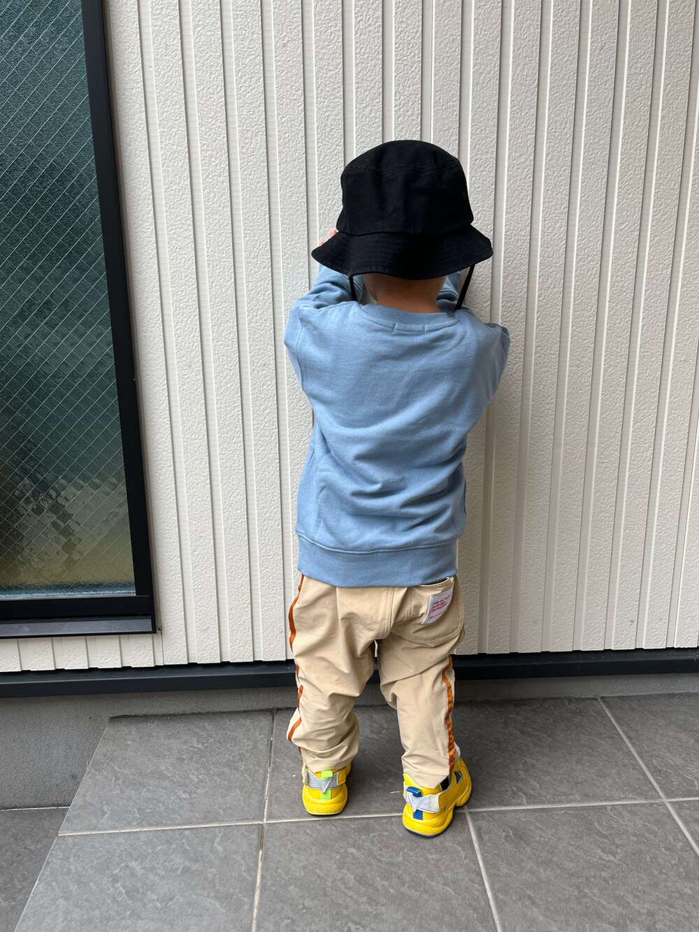 ブルー系のスウェット、ベージュ系のパンツ、イエロー系のスニーカーを着用したキッズの秋コーディネートの3枚目の写真