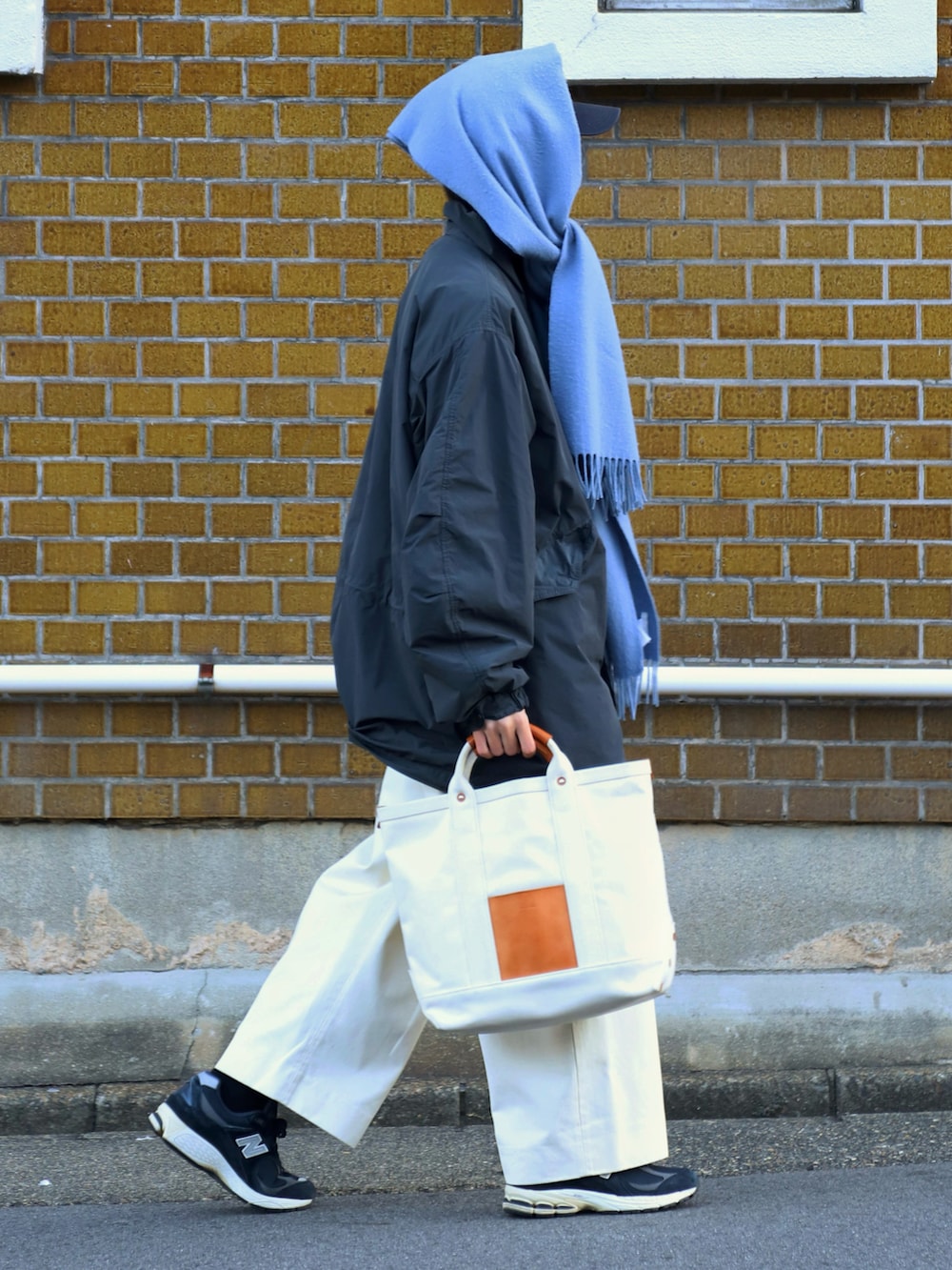 グレー系のモッズコート、ベージュ系のハンドバッグ、ホワイト系のチノパンツを着用したメンズの冬コーディネートの2枚目の写真