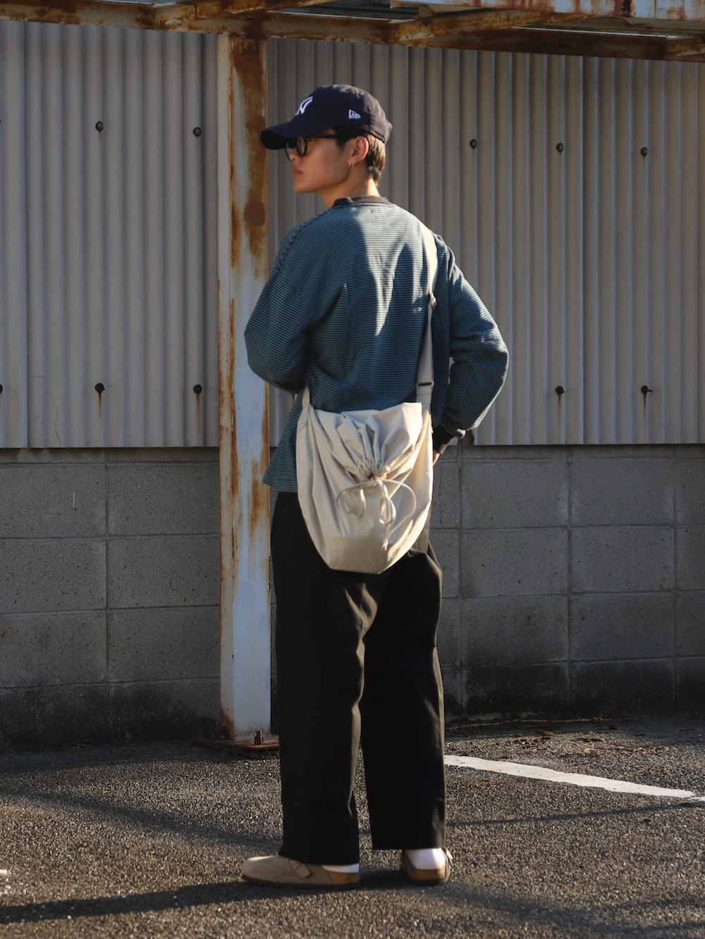 グリーン系のTシャツ/カットソー、ブラック系のチノパンツ、ベージュ系のサンダルを着用したメンズの冬コーディネートの2枚目の写真