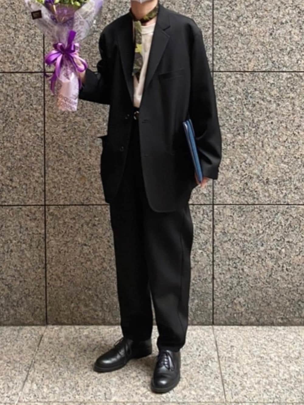 ブラック系のテーラードジャケット、ホワイト系のTシャツ/カットソー、ブラック系のスラックスを着用したメンズの春コーディネートの2枚目の写真