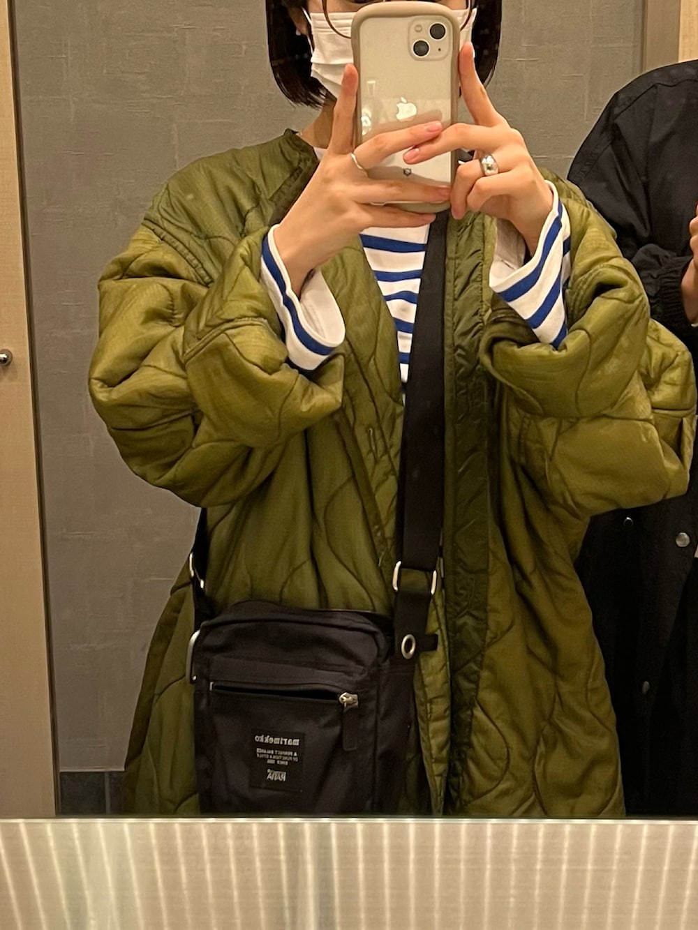 グリーン系のジャケット/アウター、ホワイト系のスニーカー、グレー系のデニムパンツを着用したレディースの秋コーディネートの2枚目の写真