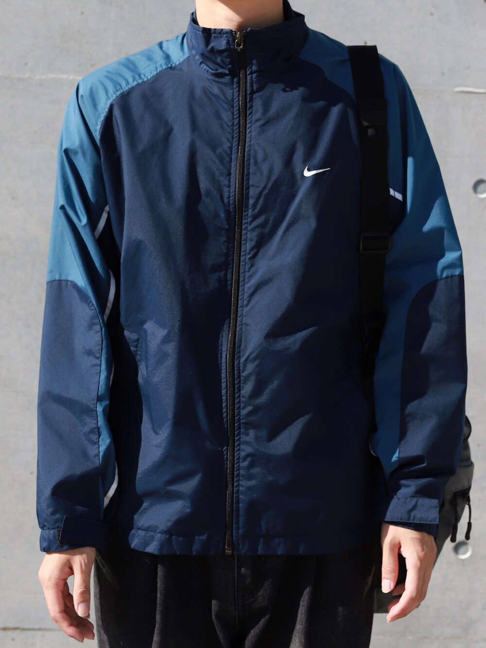 ブルー系のブルゾン、グレー系のショルダーバッグ、ブラック系のデニムパンツを着用したメンズの秋コーディネートの4枚目の写真