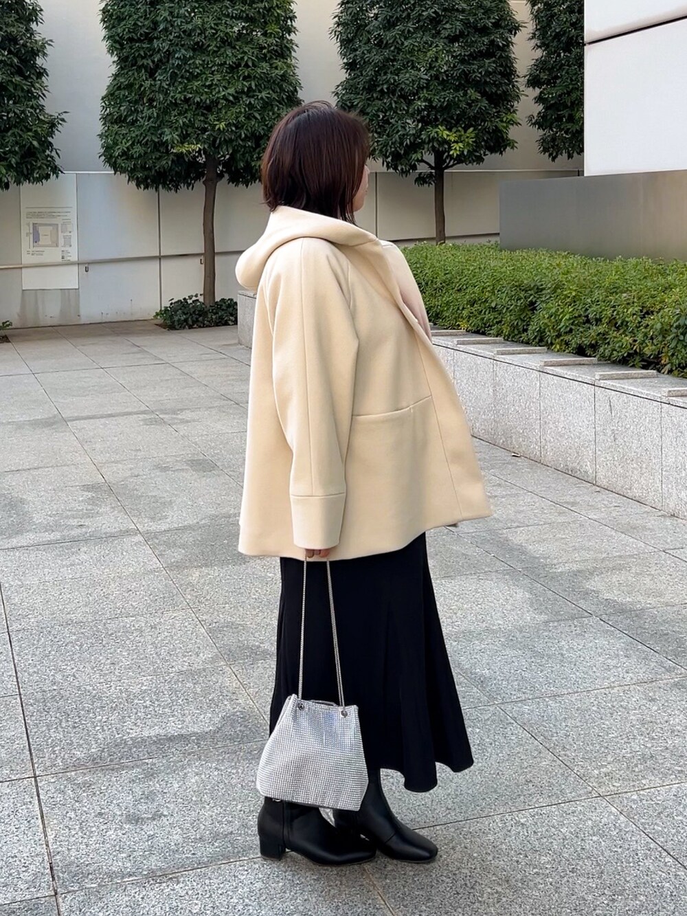 ベージュ系のその他アウター、レッド系のニット/セーター、ブラック系のスカートを着用したレディースの冬コーディネートの2枚目の写真