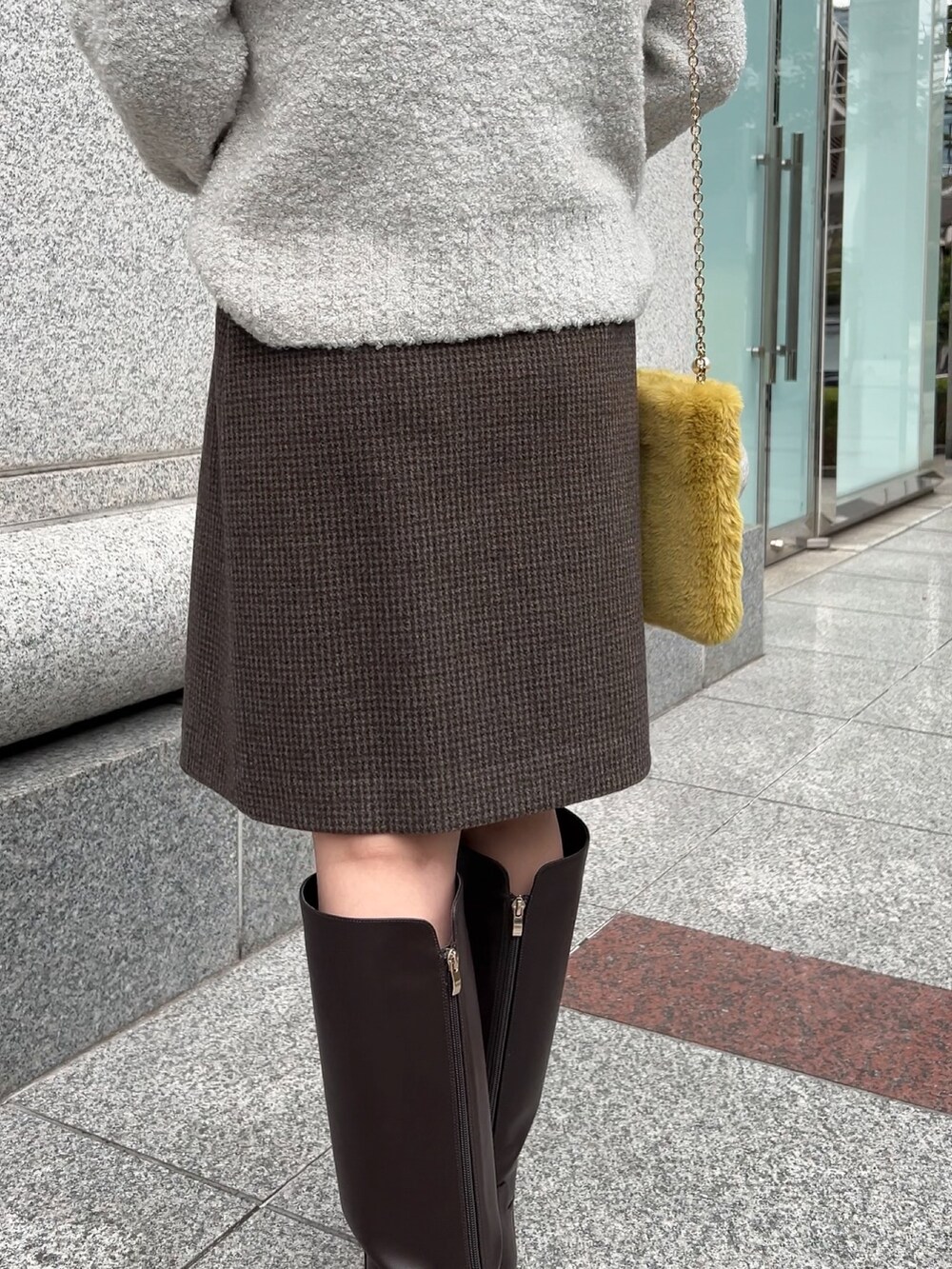 ブラウン系のブーツ、グレー系のニット/セーター、グレー系のスカートを着用したレディースの冬コーディネートの4枚目の写真