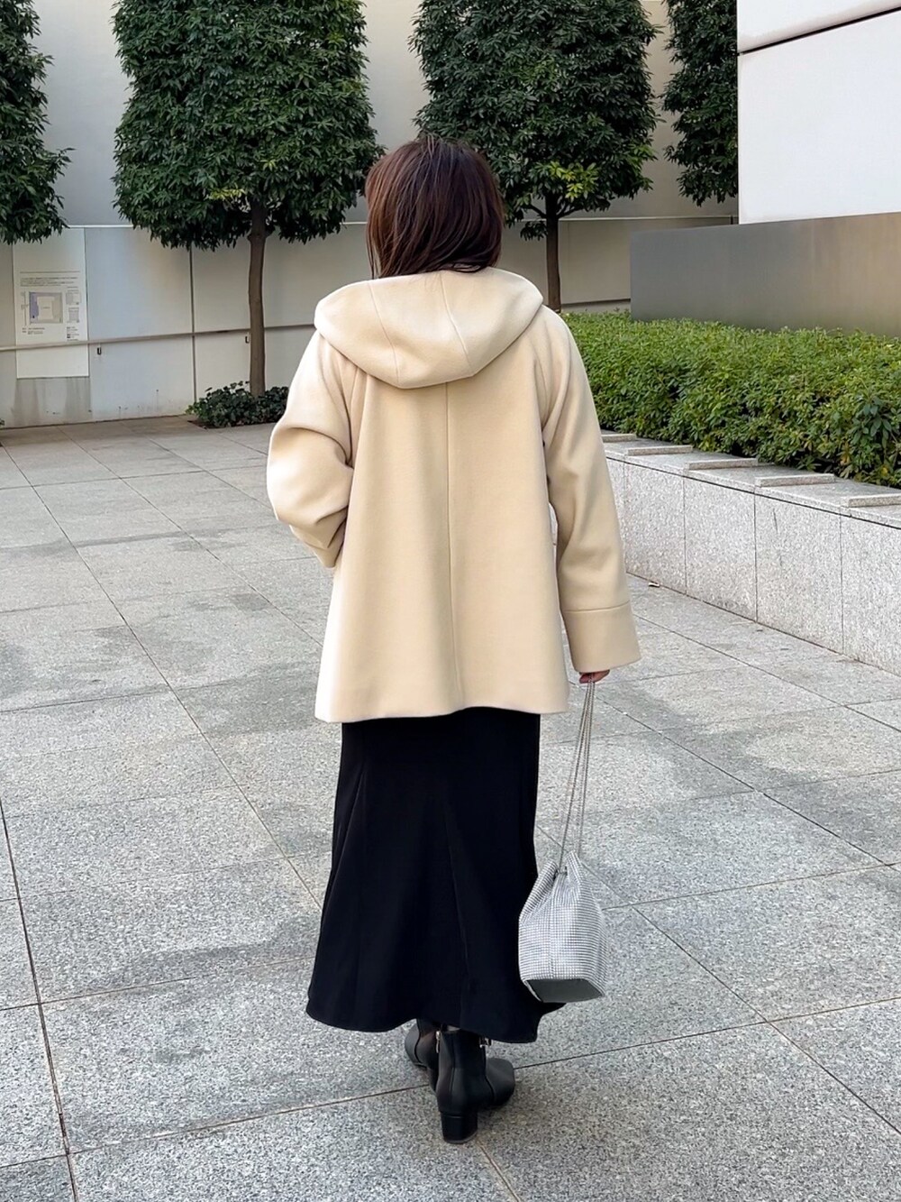 ベージュ系のその他アウター、レッド系のニット/セーター、ブラック系のスカートを着用したレディースの冬コーディネートの3枚目の写真