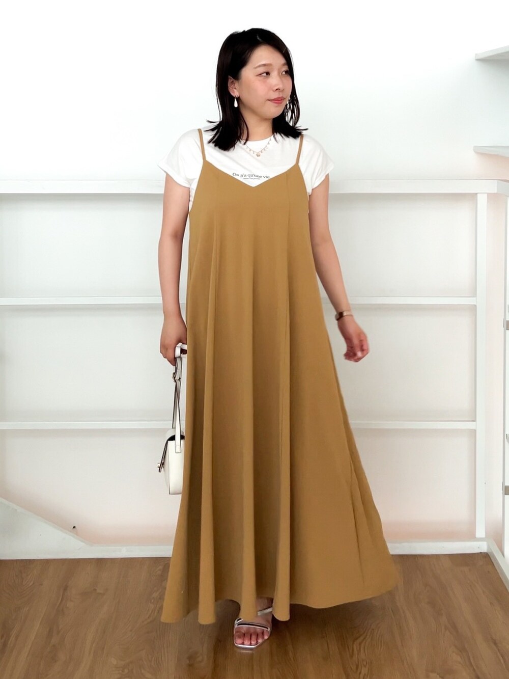 イエロー系のワンピース、ホワイト系のショルダーバッグ、シルバー系のサンダルを着用したレディースの夏コーディネートの2枚目の写真