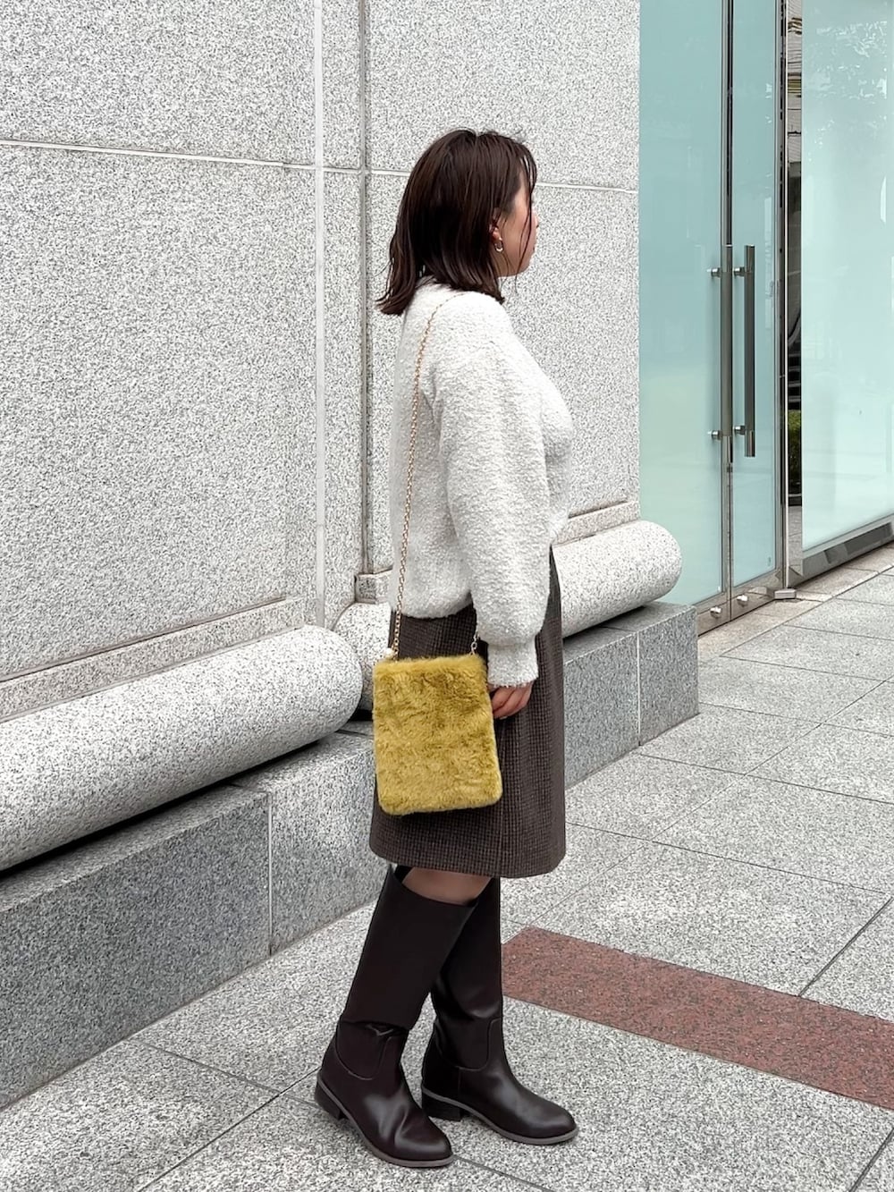 ブラウン系のブーツ、グレー系のニット/セーター、グレー系のスカートを着用したレディースの冬コーディネートの6枚目の写真