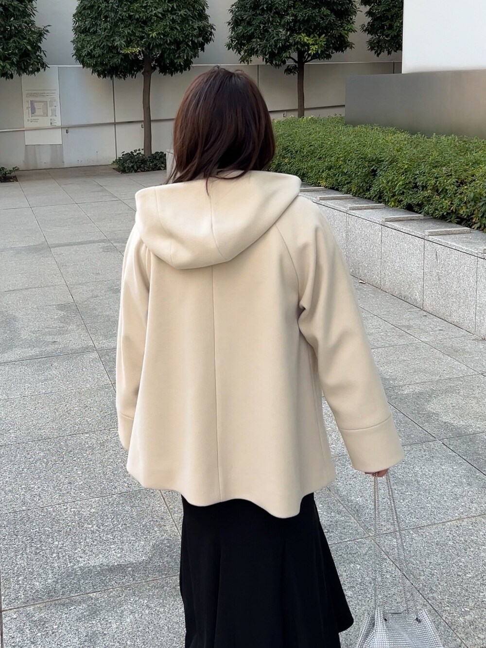 ベージュ系のその他アウター、レッド系のニット/セーター、ブラック系のスカートを着用したレディースの冬コーディネートの6枚目の写真