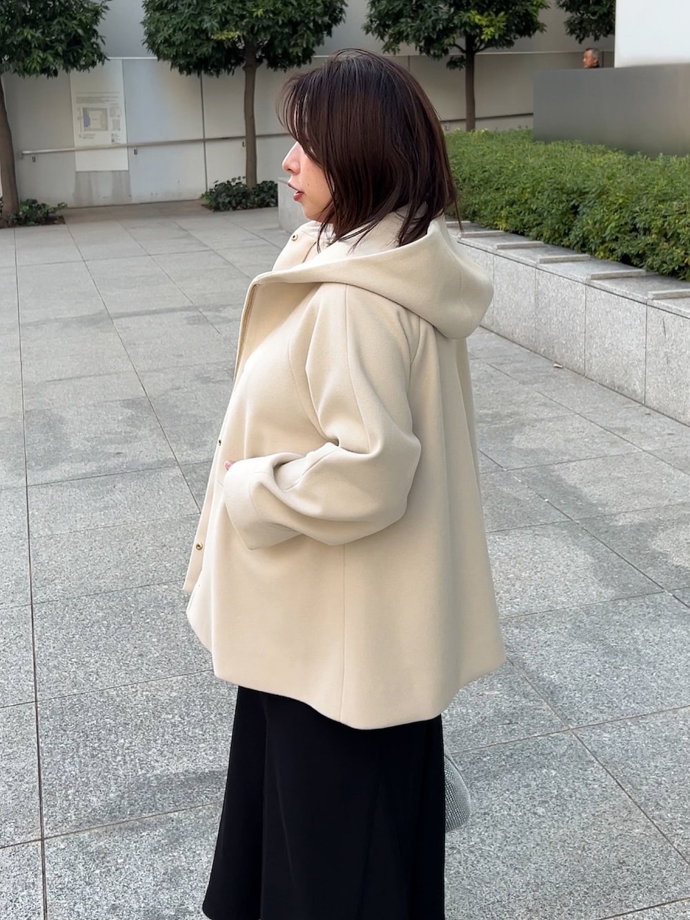 ベージュ系のその他アウター、レッド系のニット/セーター、ブラック系のスカートを着用したレディースの冬コーディネートの5枚目の写真