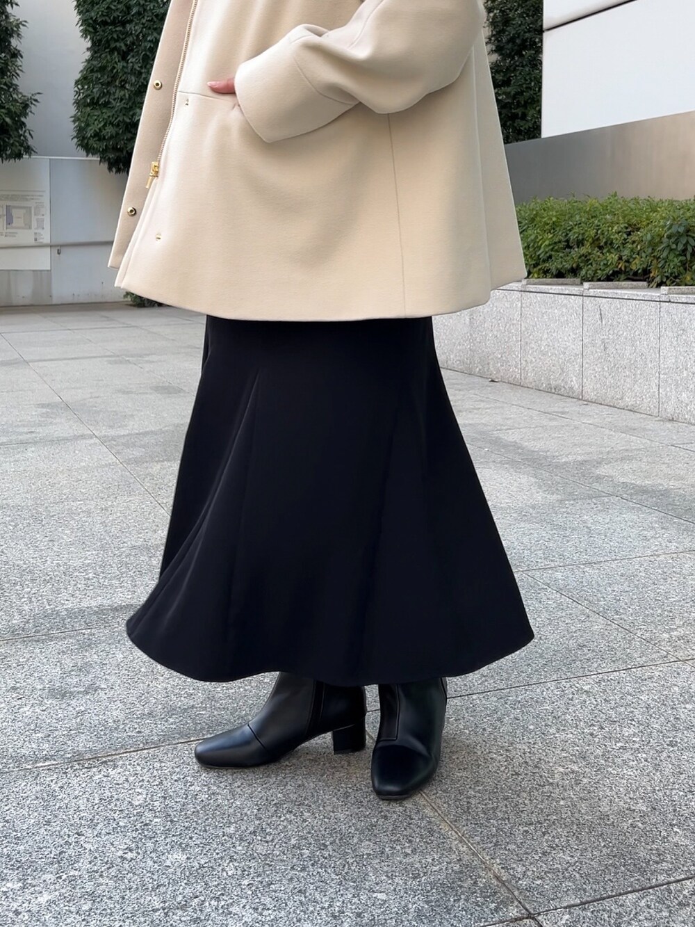 ベージュ系のその他アウター、レッド系のニット/セーター、ブラック系のスカートを着用したレディースの冬コーディネートの8枚目の写真