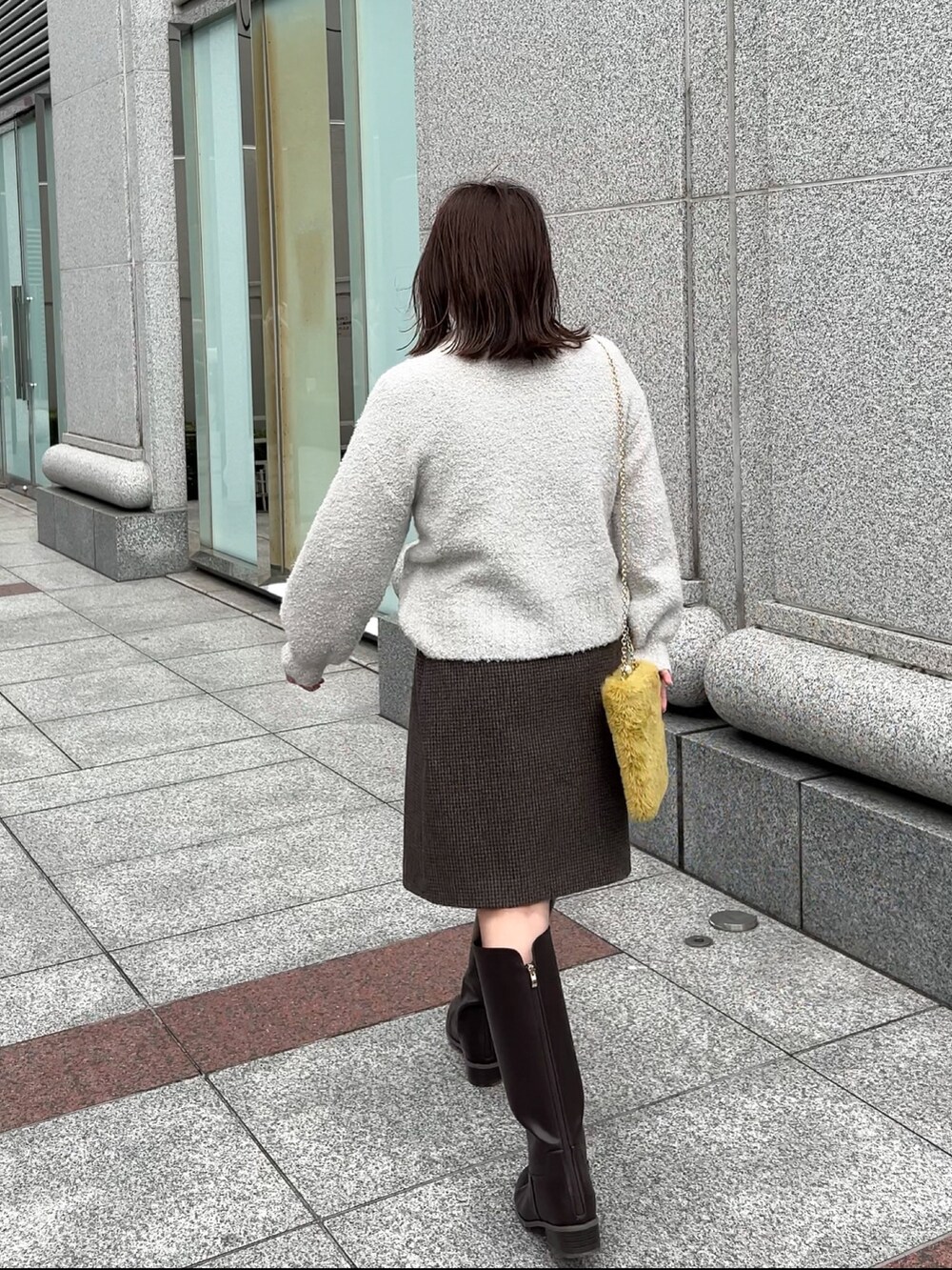 ブラウン系のブーツ、グレー系のニット/セーター、グレー系のスカートを着用したレディースの冬コーディネートの5枚目の写真