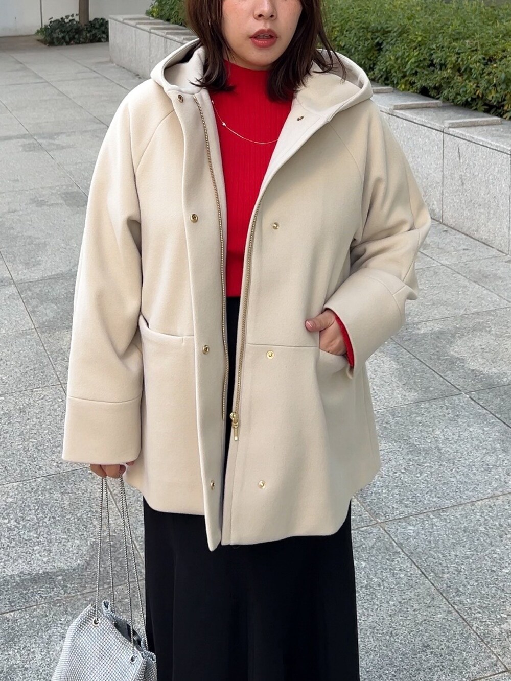 ベージュ系のその他アウター、レッド系のニット/セーター、ブラック系のスカートを着用したレディースの冬コーディネートの4枚目の写真