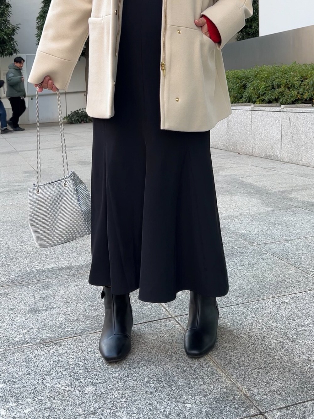 ベージュ系のその他アウター、レッド系のニット/セーター、ブラック系のスカートを着用したレディースの冬コーディネートの7枚目の写真