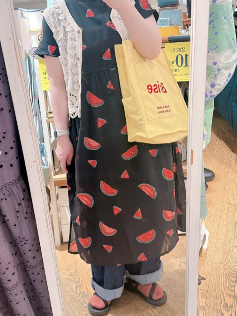 イエロー系のトートバッグ、ブラック系のワンピースを着用したレディースの夏コーディネートの5枚目の写真