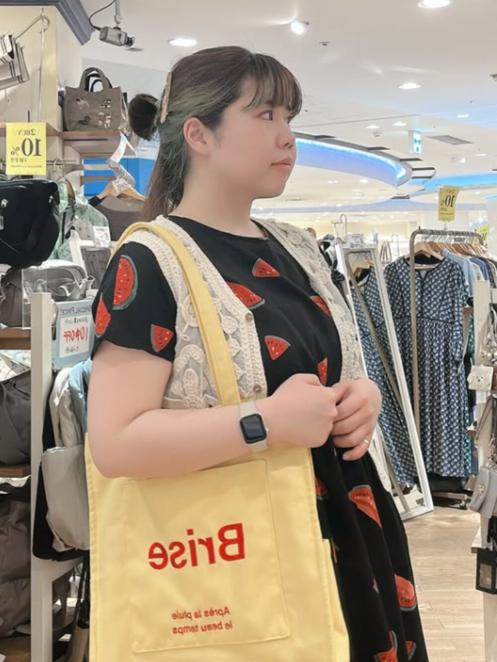 イエロー系のトートバッグ、ブラック系のワンピースを着用したレディースの夏コーディネートの3枚目の写真