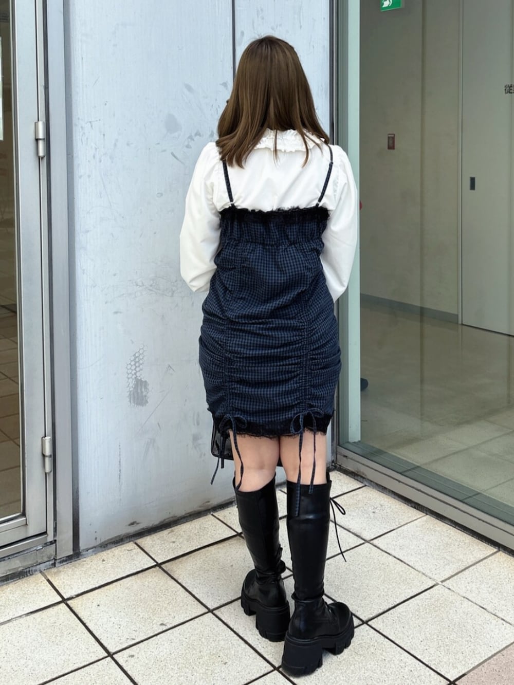 ブラック系のハンドバッグ、ブラック系のブーツ、ブルー系のワンピースを着用したレディースの春コーディネートの5枚目の写真