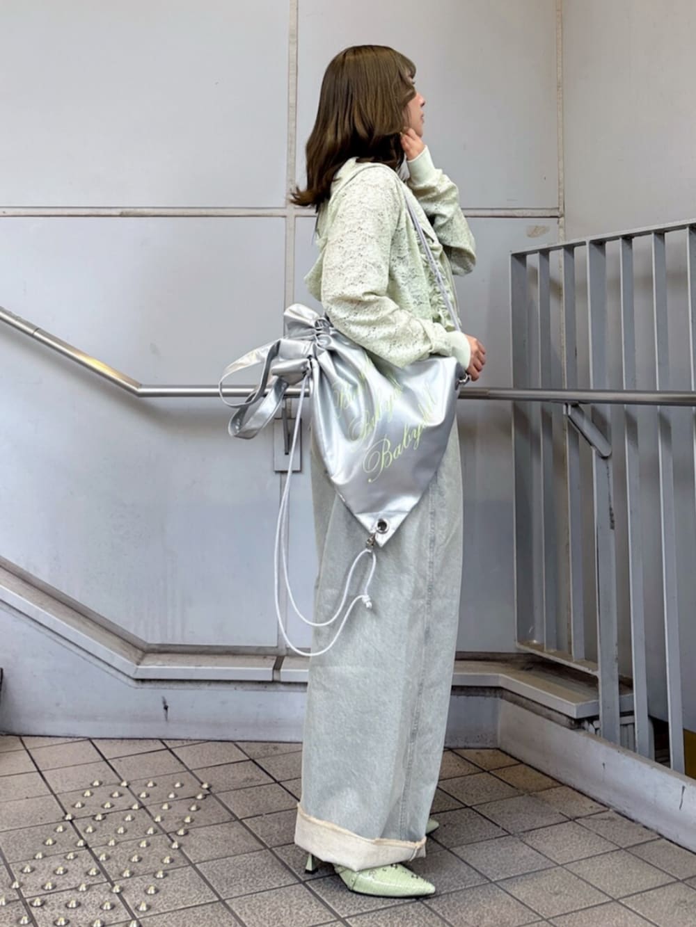 グリーン系のパーカー、ブラック系のキャミソール、ブルー系のデニムパンツを着用したレディースの春コーディネートの3枚目の写真