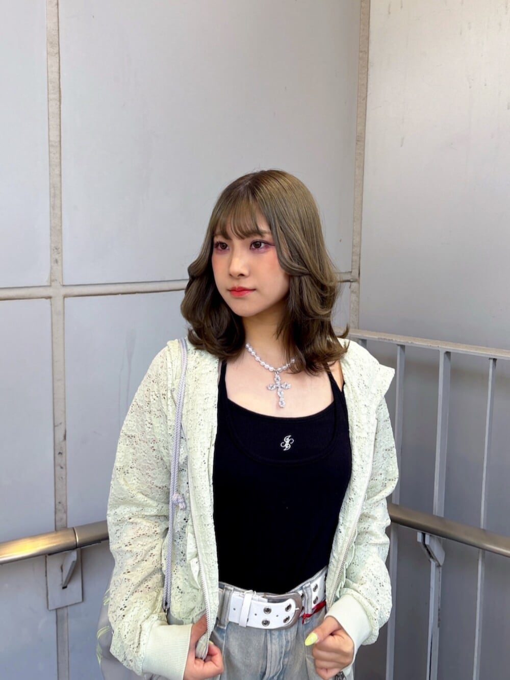 グリーン系のパーカー、ブラック系のキャミソール、ブルー系のデニムパンツを着用したレディースの春コーディネートの5枚目の写真