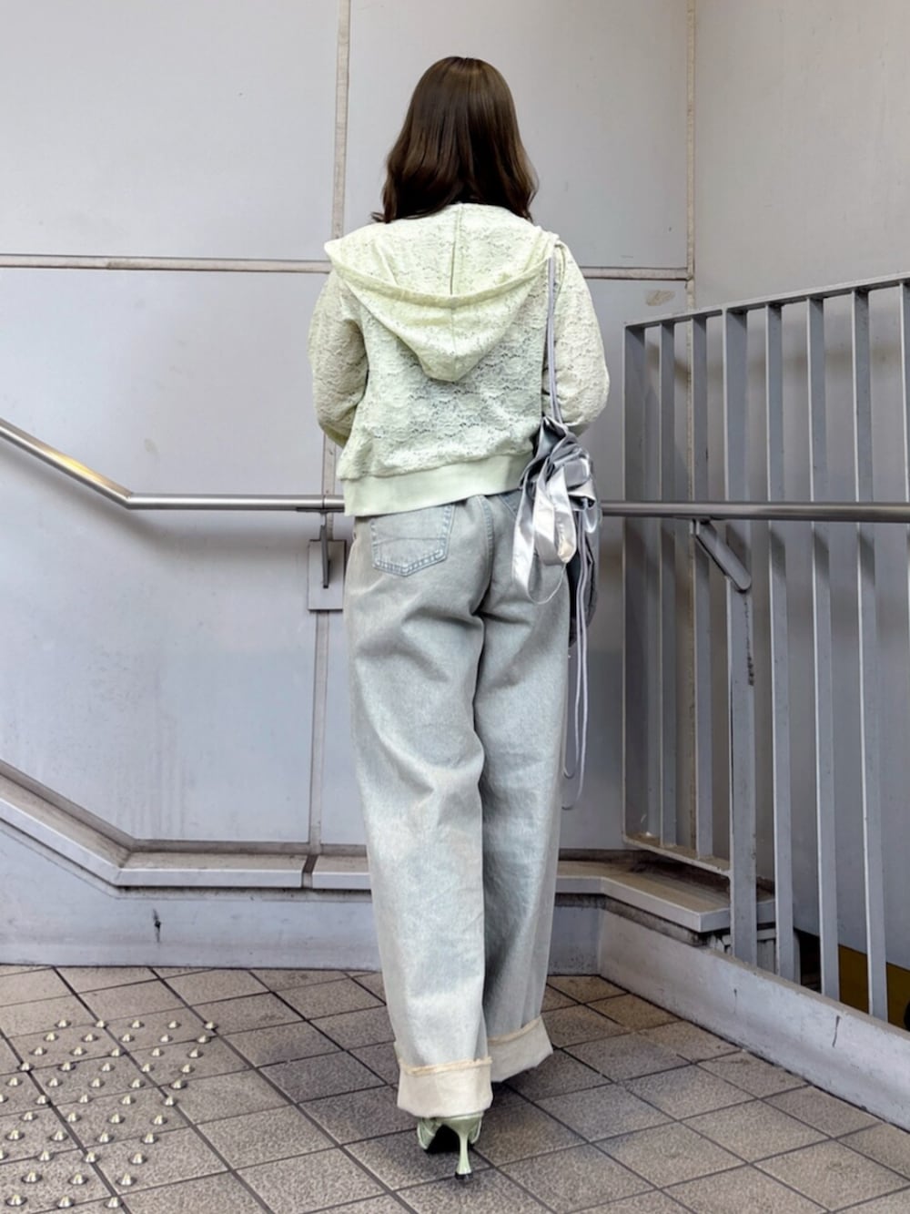 グリーン系のパーカー、ブラック系のキャミソール、ブルー系のデニムパンツを着用したレディースの春コーディネートの4枚目の写真