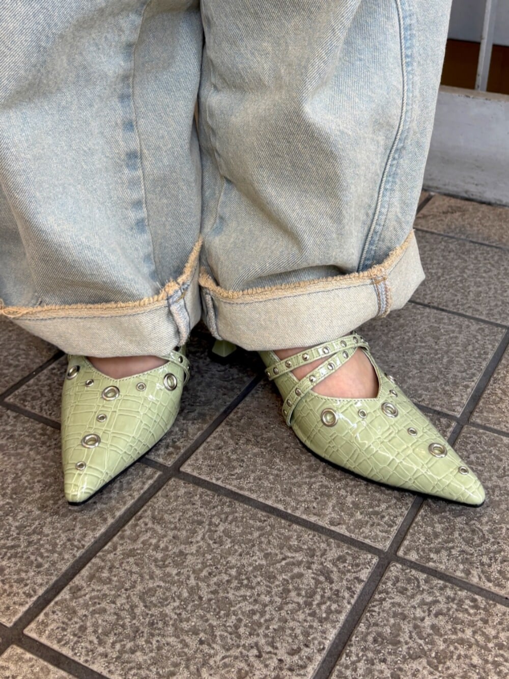 グリーン系のパーカー、ブラック系のキャミソール、ブルー系のデニムパンツを着用したレディースの春コーディネートの10枚目の写真