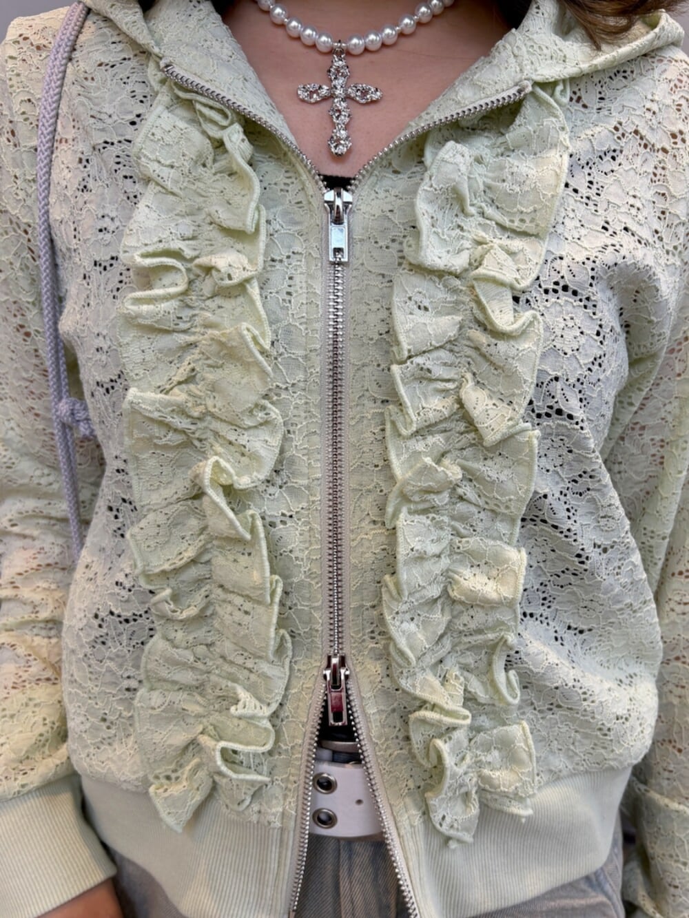 グリーン系のパーカー、ブラック系のキャミソール、ブルー系のデニムパンツを着用したレディースの春コーディネートの7枚目の写真