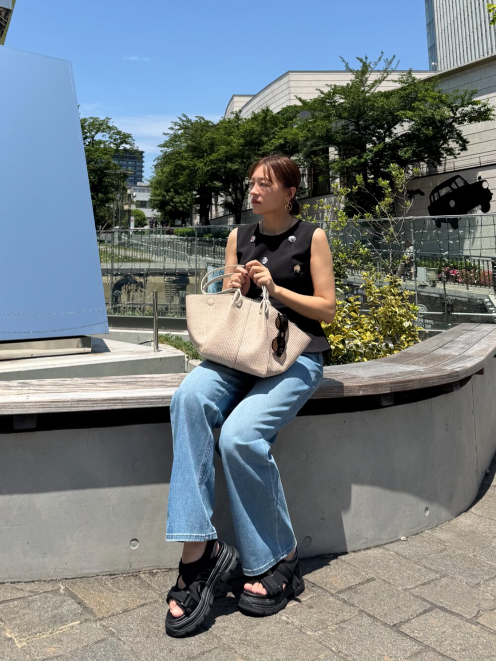 ホワイト系のトートバッグ、ブルー系のデニムパンツ、ブラック系のタンクトップを着用したレディースの夏コーディネートの4枚目の写真