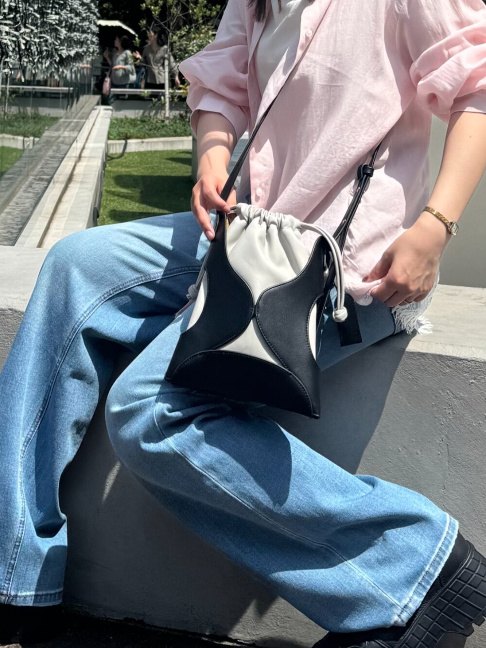 ブラック系のショルダーバッグ、ブルー系のデニムパンツ、ピンク系のシャツ/ブラウスを着用したレディースの夏コーディネートの4枚目の写真