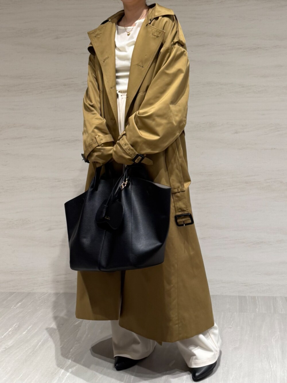 ホワイト系のTシャツ/カットソー、ホワイト系のスラックス、イエロー系のトレンチコートを着用したレディースの冬コーディネートの10枚目の写真