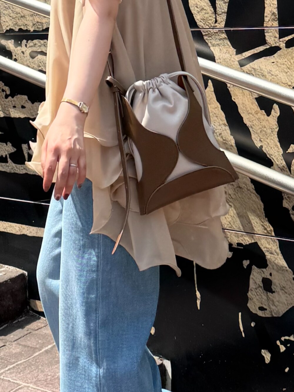 イエロー系のショルダーバッグ、ブルー系のデニムパンツ、ベージュ系のキャミソールを着用したレディースの夏コーディネートの8枚目の写真