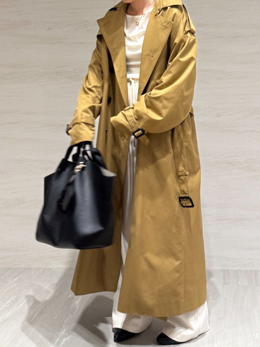 ホワイト系のTシャツ/カットソー、ホワイト系のスラックス、イエロー系のトレンチコートを着用したレディースの冬コーディネートの9枚目の写真