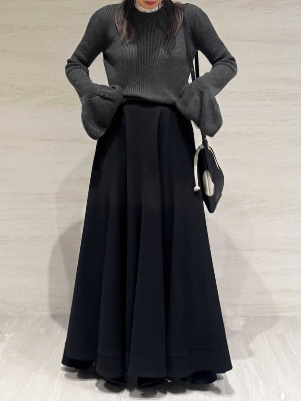 ブラック系のスカート、グレー系のニット/セーター、ブラック系のショルダーバッグを着用したレディースの秋コーディネートの4枚目の写真