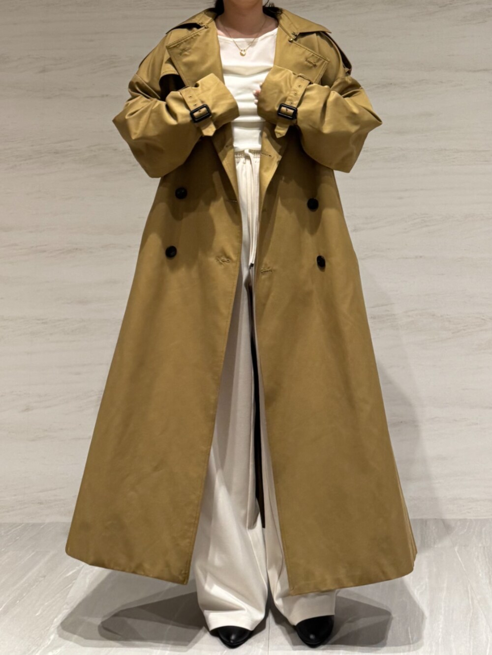 ホワイト系のTシャツ/カットソー、ホワイト系のスラックス、イエロー系のトレンチコートを着用したレディースの冬コーディネートの5枚目の写真