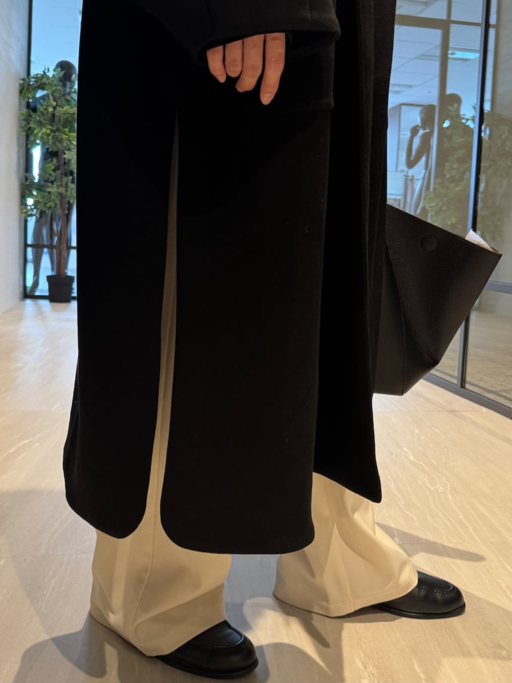 ブラック系のトートバッグ、ブラック系のニット/セーター、ブラック系のチェスターコートを着用したレディースの秋コーディネートの3枚目の写真