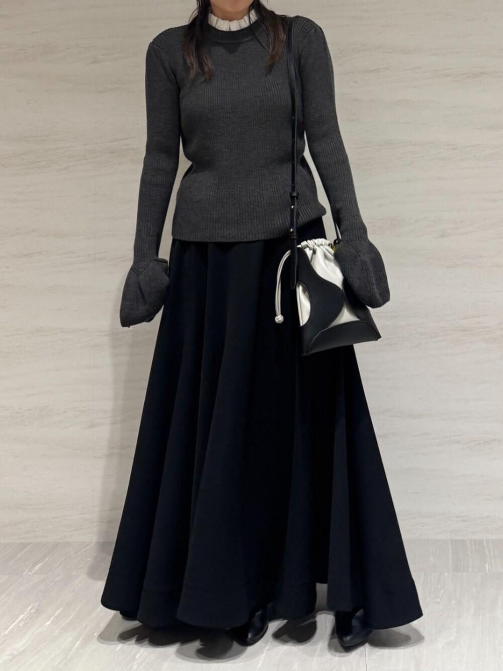 ブラック系のスカート、グレー系のニット/セーター、ブラック系のショルダーバッグを着用したレディースの秋コーディネートの3枚目の写真
