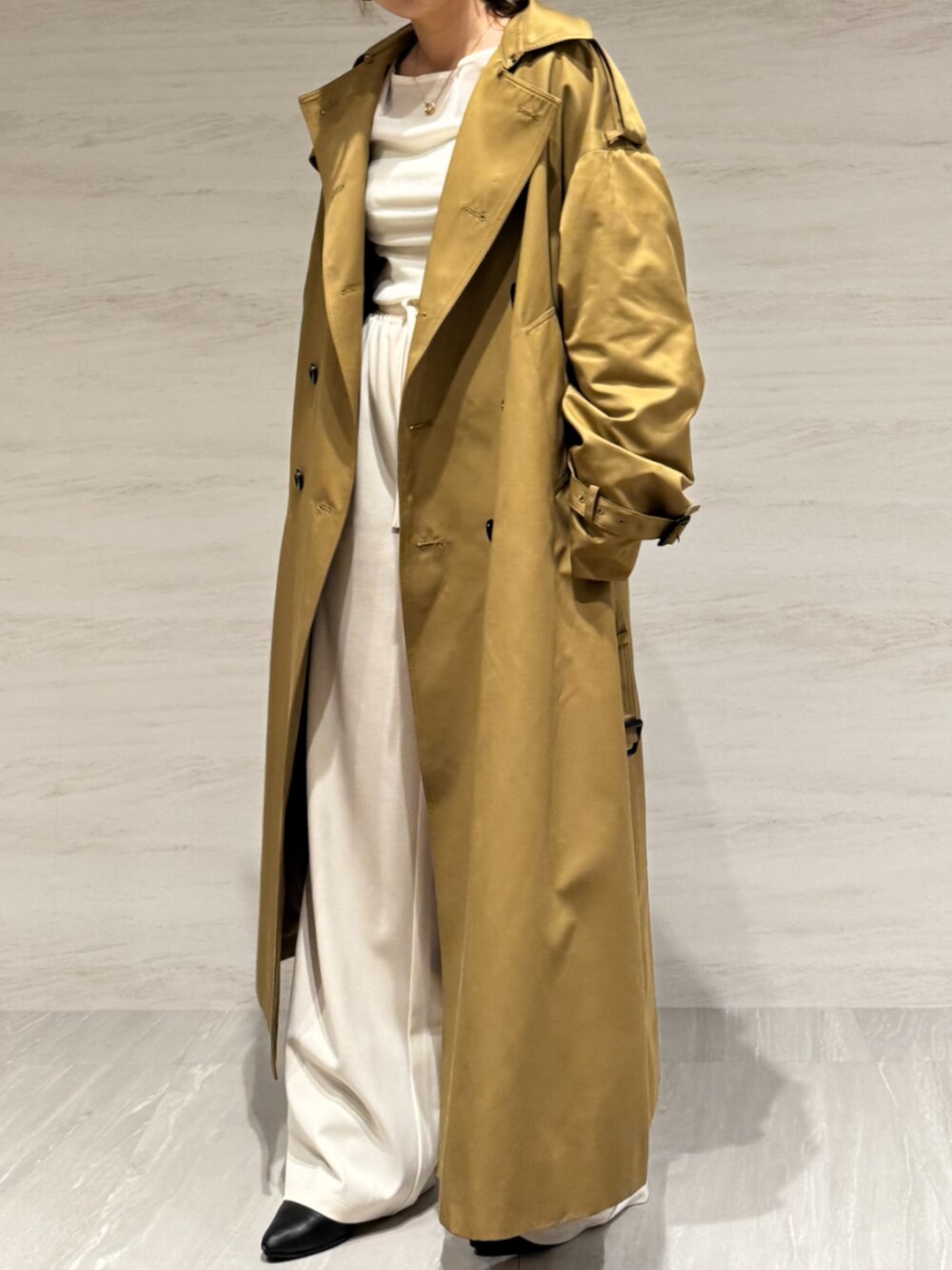 ホワイト系のTシャツ/カットソー、ホワイト系のスラックス、イエロー系のトレンチコートを着用したレディースの冬コーディネートの3枚目の写真