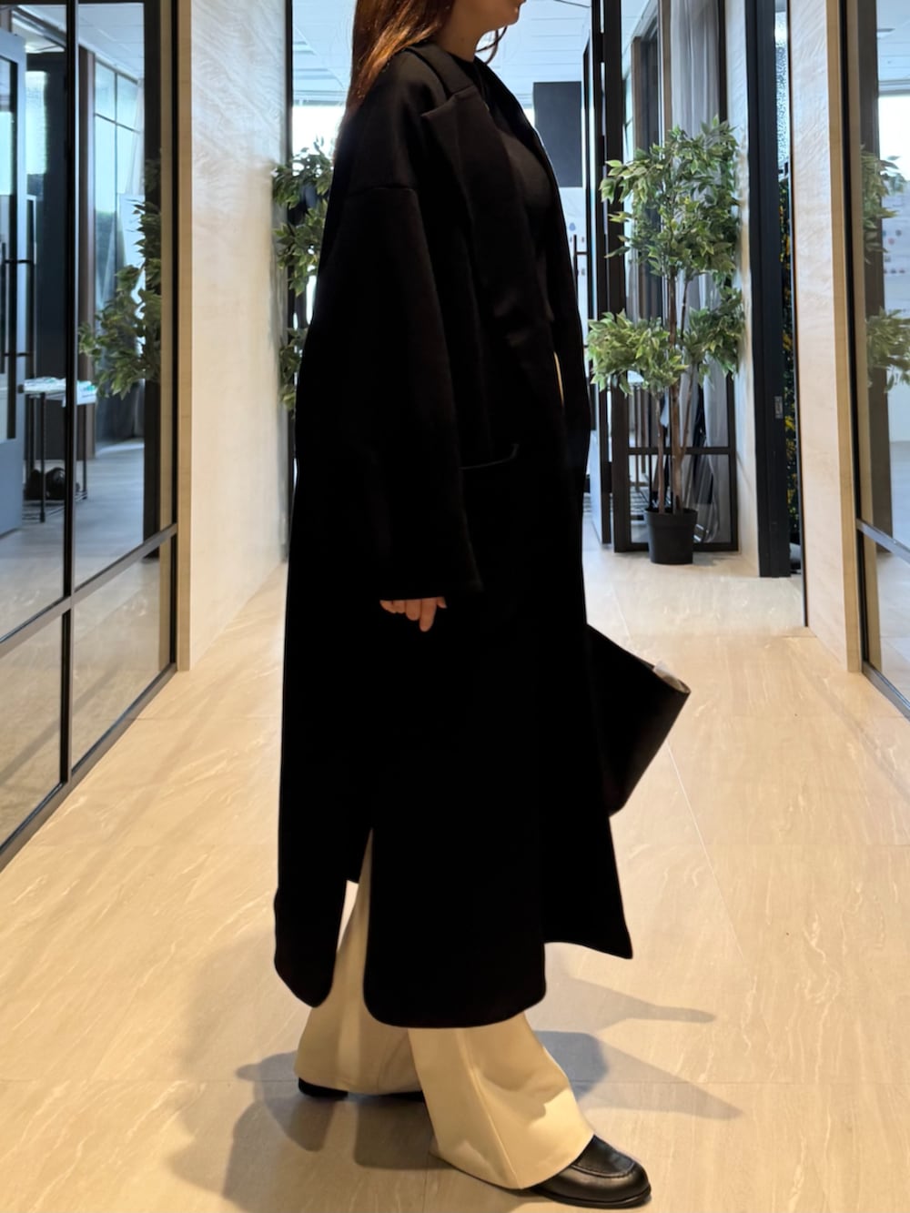 ブラック系のトートバッグ、ブラック系のニット/セーター、ブラック系のチェスターコートを着用したレディースの秋コーディネートの2枚目の写真